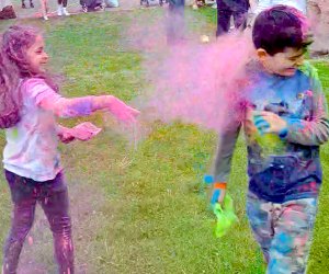 kids tossing bright colors on each other in a field of grass