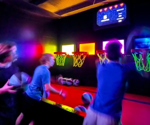 Teens playing a shooting game at Activate, neon, arcade, sports