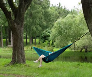 girl relaxing in a portable hammock by a stream for Hammock Day 