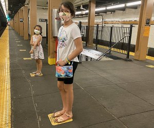 Two girls stand on empty New York City subway platform