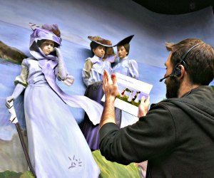 A pageant sculptor helps volunteer cast members into their poses at a rehearsal 