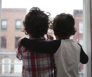 two boys looking out a window with their arms around each other