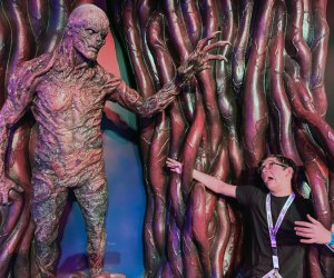 Image of child with Vecna statue from Stranger Things exhibit.