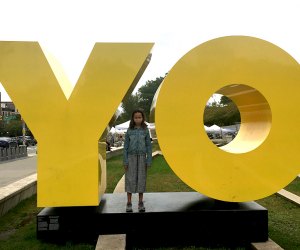 girl standing between YO sign