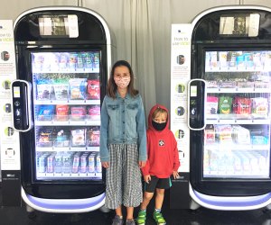 girl and boy kids standing at AI-inspired vending machines