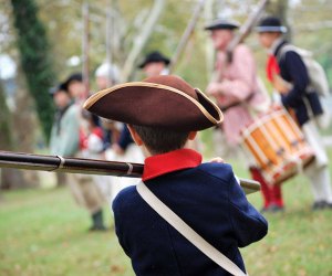 boy dressed in period costume watching a marching band