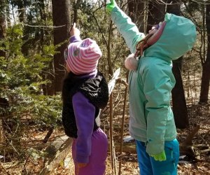 Two girls in the woods pointing at wildlife Greenburgh Nature Center Westchester winter walks