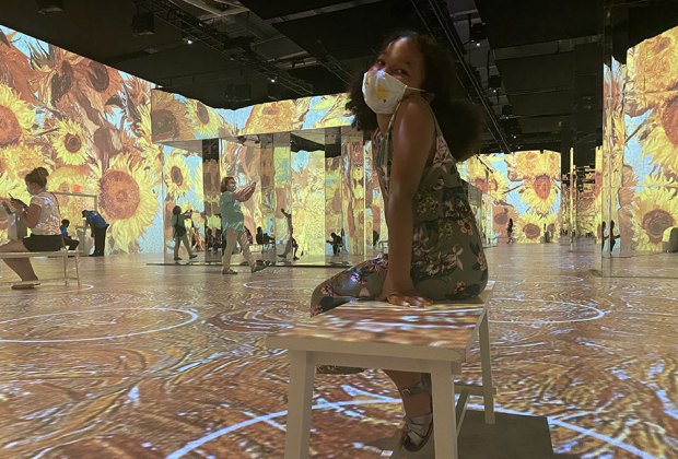 Girl smiles surrounded by Van Gogh's sunflowers