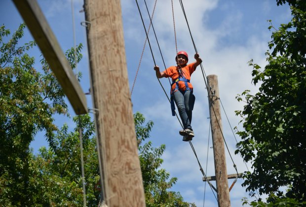 een bezoeker wandelt de high rope bij Alley Pond Adventure Course