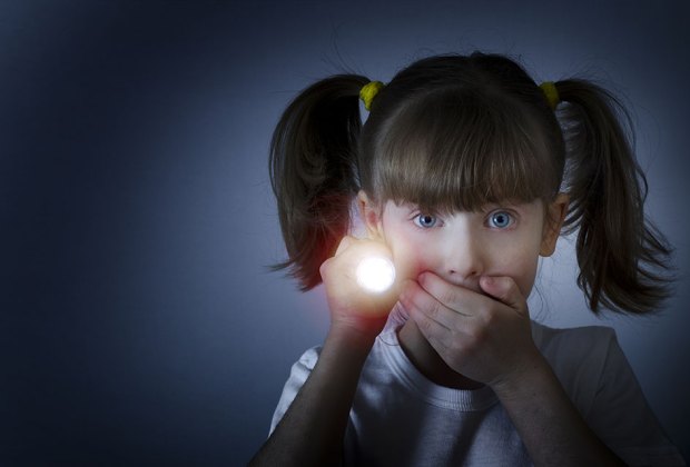 girl looking quiet while holding flashlight in the dark