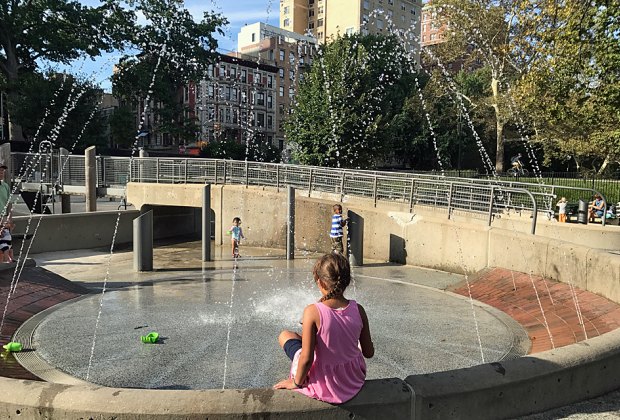 Girl perched on edge of water feature in Central Park's Tarr Family Playground