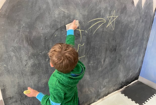 Boy drawing on chalk wall at The Kiddie Clubhouse