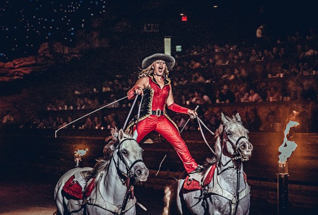 woman performs a horse a show in front of an audience Dolly Parton's Stampede