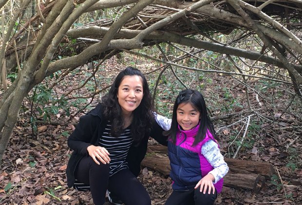 mom and daughter hiking through a woods tunnel