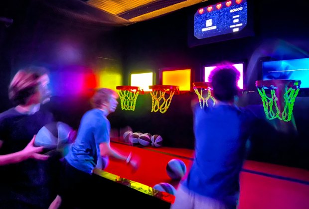 Teens playing a shooting game at Activate, neon, arcade, sports