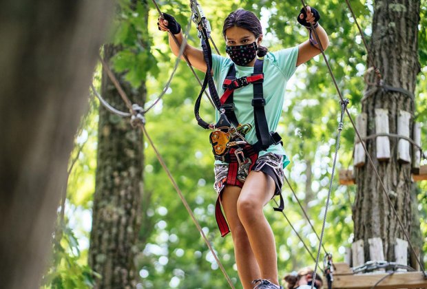 Girl in mask crosses Roap Bridge at Mountain Creek 's adventure course's adventure course