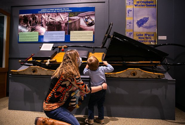  The Olympic Museum Mom and son looking at exhibit Things to Do in Lake Placid on a Winter Vacation Status message