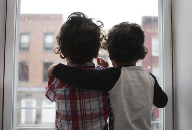 two boys looking out a window with their arms around each other