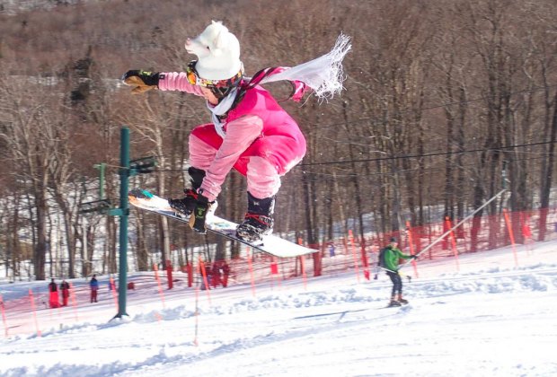 Image of snowboarder jumping on slope at New England ski resort.