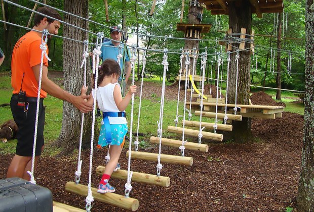 Jovem percorre de baixo-para-o-terreno ponte de corda em Pocono TreeVentures