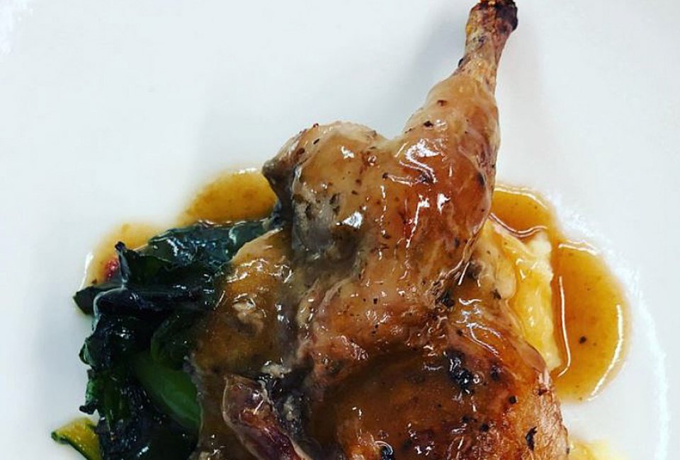 Photo of a plated roast duck leg in sauce