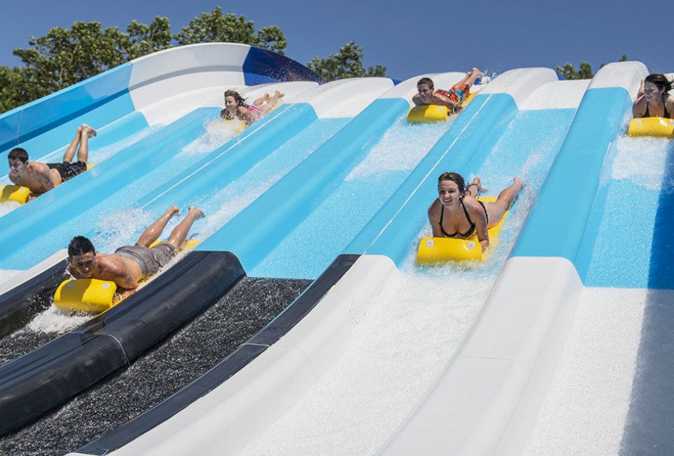 people slide down the big wave racer slides at the water park