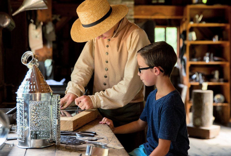 Tinsmiths show children the authentic process of transforming metal sheets into household items. Photo courtesy of Old Sturbridge Village