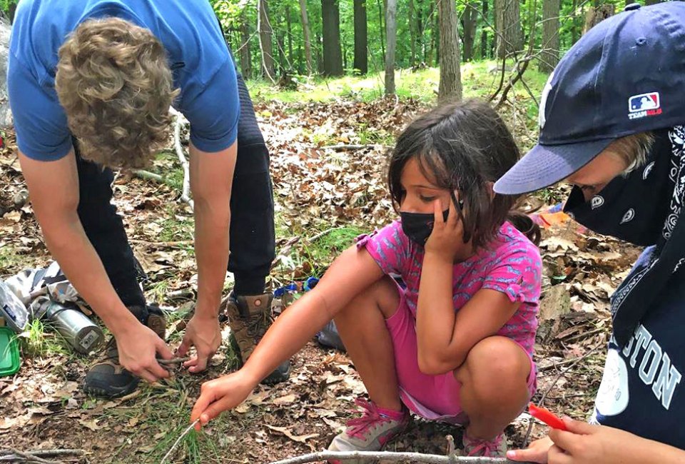 Roasting lunch over the fire - covid style with masks at the Rewilding School. Photo courtesy of the school